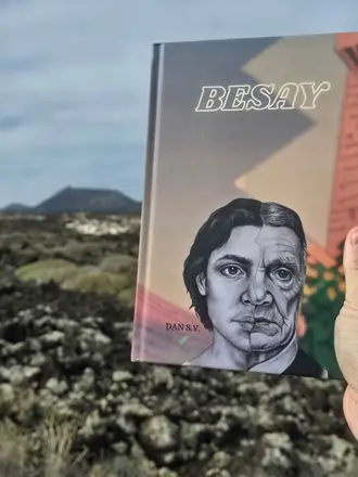 Ejemplar de Besay sostenido en alto frente a un paisaje volcánico, con un cono volcánico al fondo y el cielo nublado.
