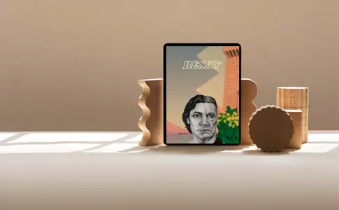 Portada de Besay en una tablet apoyada entre piezas decorativas de madera, sobre fondo beige.