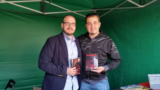Dan S. V. posa con un ejemplar de Xerhon-Ra junto a otro hombre que sostiene el suyo, bajo una carpa verde.